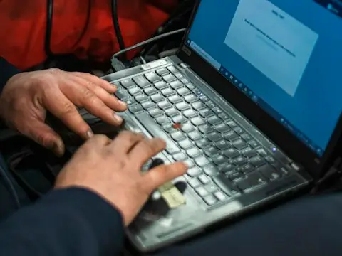 homem sentado em um carro usando um computador