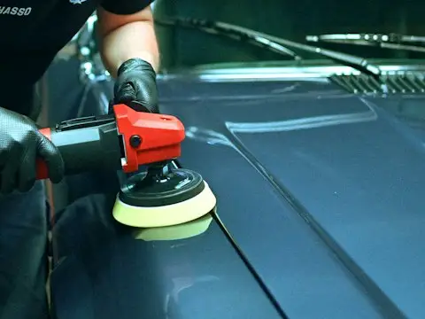 Pessoa polindo o capô de um carro azul com uma politriz