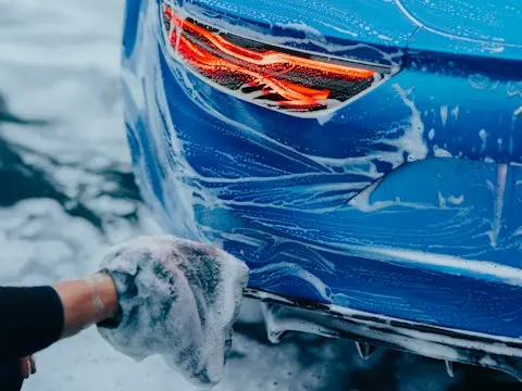 uma pessoa lavando um carro azul com um pano