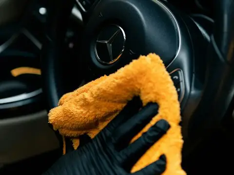 Uma pessoa limpando um carro com um pano amarelo