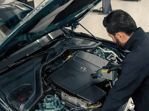 Mecânico inspecionando um motor de carro com capô aberto